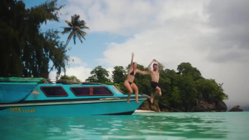Two travellers jumping into the sea from a small passenger boat